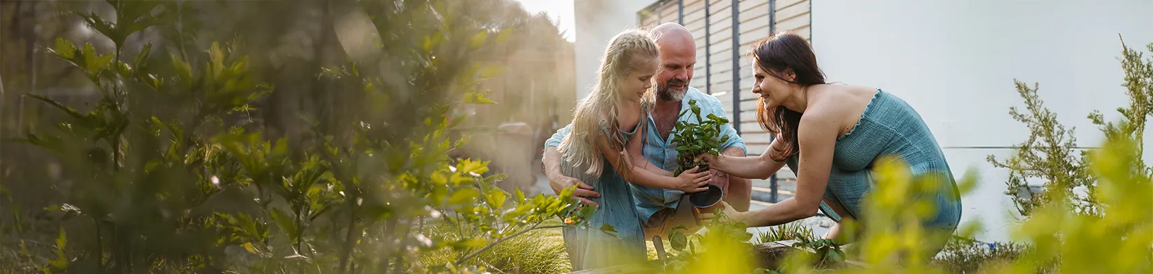 Eine Familie ist im Garten und topft Pflanzen um. Bei ihrer Immobilie steht bald die Anschlussfinanzierung im Raum.