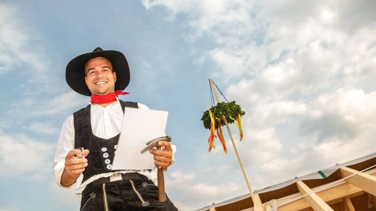 Ein Handwerker hält eine Rede beim Richtfest.