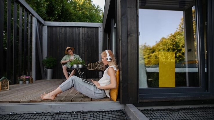 Das Foto zeigt zwei Personen auf der Terrasse ihres Tiny Houses. Es steht sinnbildlich für Informationen vor dem Einzug in ein Tiny House.