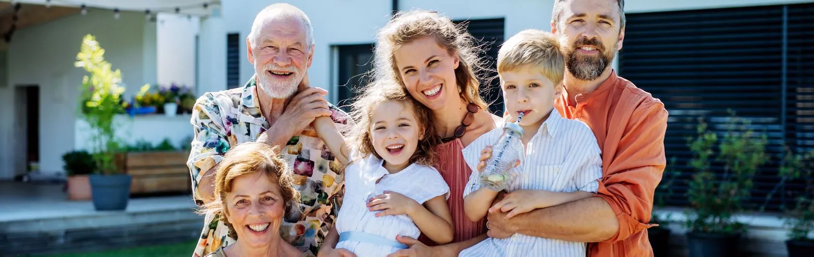 Das Foto zeigt eine glückliche vierköpfige Familie mit Großeltern und steht sinnbildlich für das Thema Mehrgenerationenhaus.