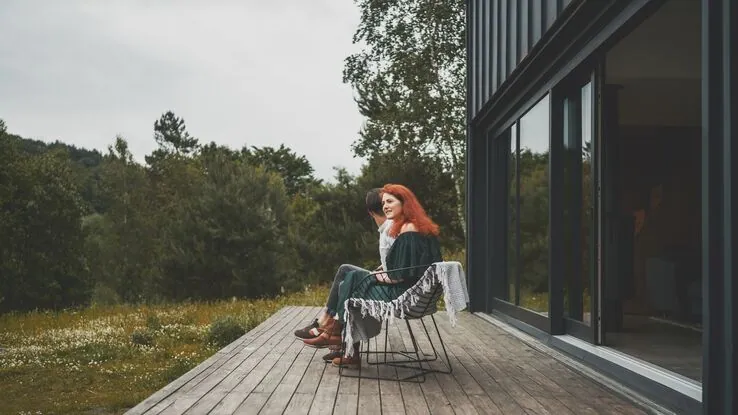 Ein Paar sitzt auf der Terrasse eines Tiny House. Sie stehen sinnbildlich für das Thema Tiny House mieten.