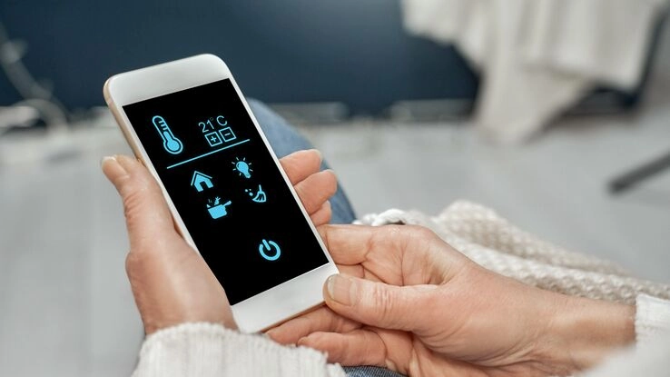 Ein Handy mit einer Smart Home App verdeutlicht den Trend für modernes Wohnen.