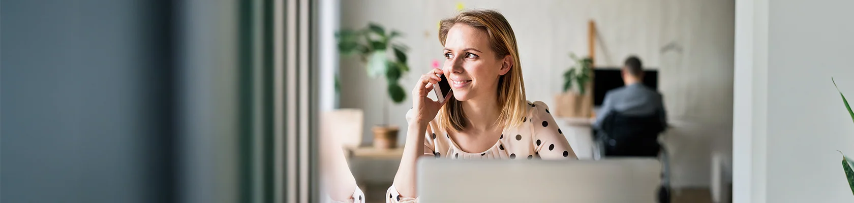 Eine Frau informiert sich am Telefon über Baufinanzierung.