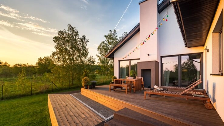 Ein Foto von einer Holzterrasse mit Möbeln im Sonnenuntergang.