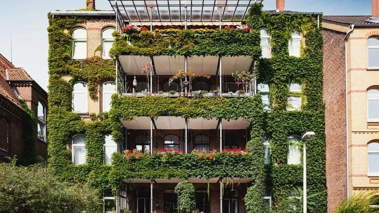 Das Foto zeigt ein Haus mit einer begrünten Fassade und symbolisiert die Vorteile einer Gebäudebegrünung.