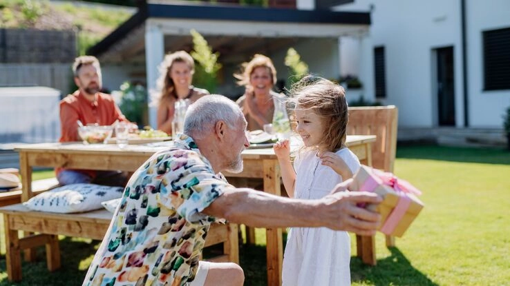 Das Foto zeigt eine Mehrgenerationenfamilie in einem Garten und steht symbolisch für das Thema Mehrgenerationenhaus.