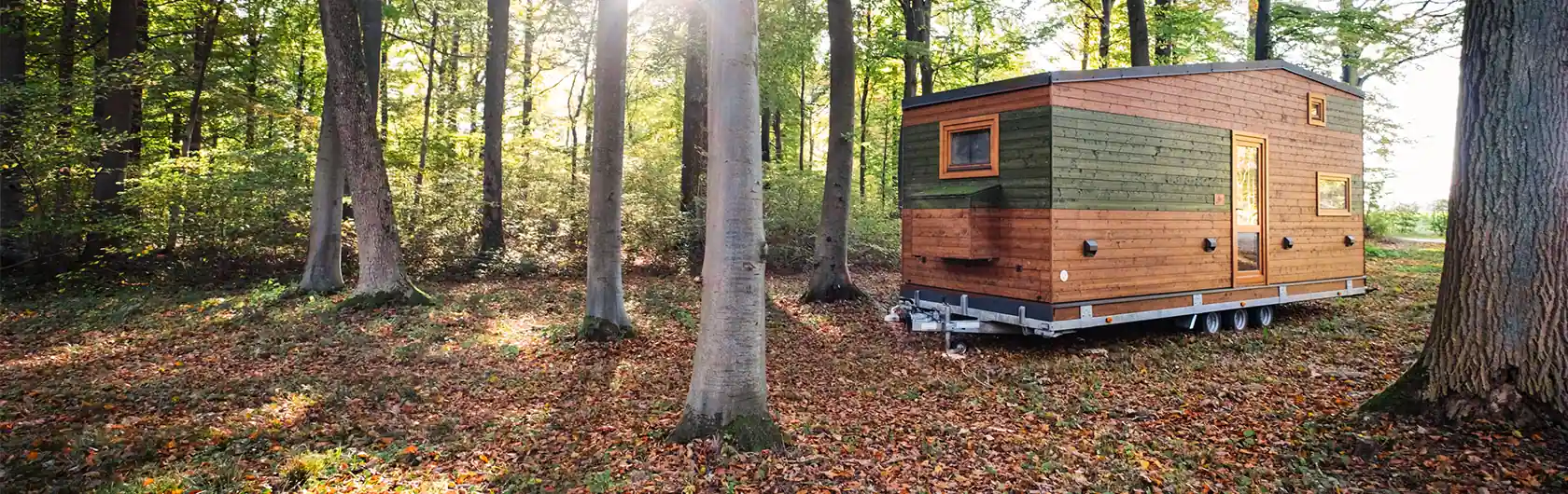 Das Foto zeigt ein Tiny House im Wald. Es steht sinnbildlich für den Bau- und Wohntrend.