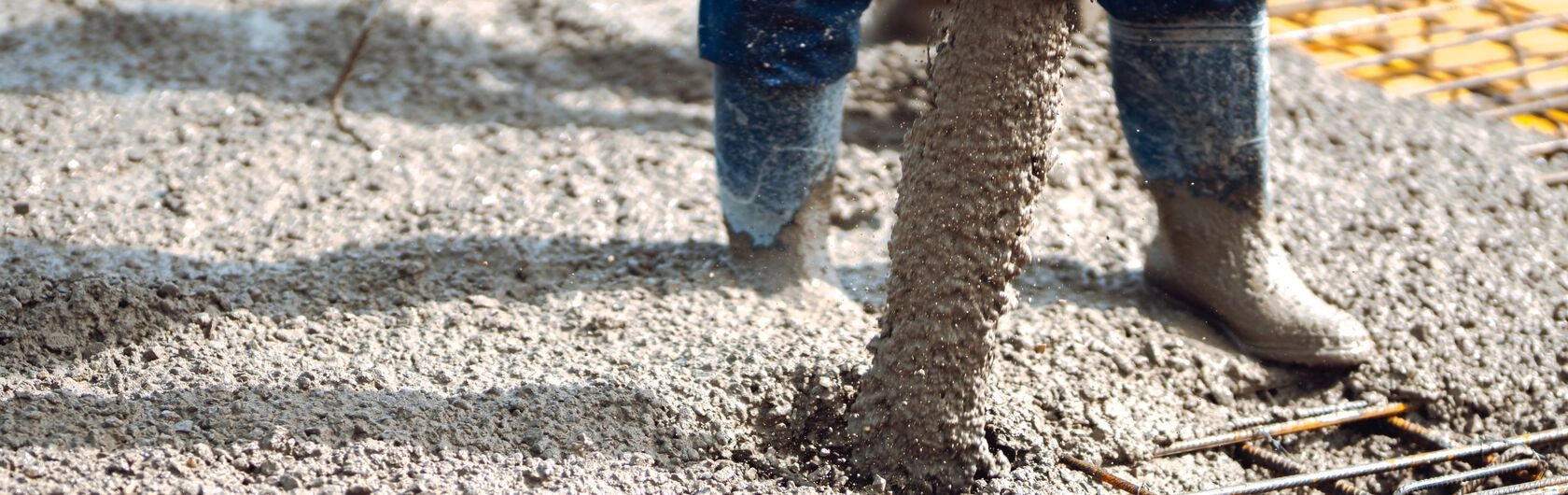 Mann schüttet Beton auf Drahtgestell