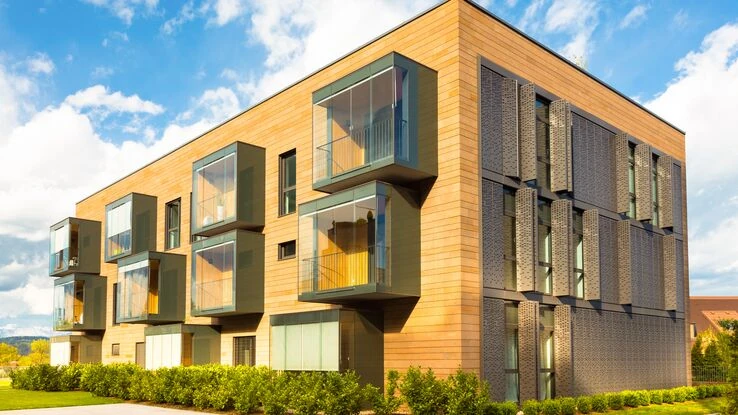 Das Bild zeigt ein modernes Gebäude aus Holz. Es steht sinnbildlich für einen nachhaltigen Wohnungsbau.