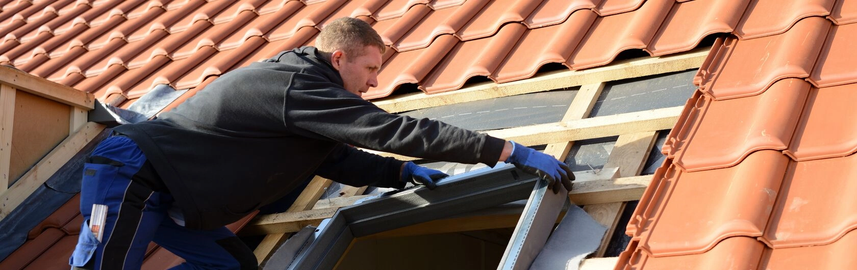 Ein Mann saniert die Fenster eines Hauses neu um die Energieeffizienz und den Wohnkomfort zu verbessern.