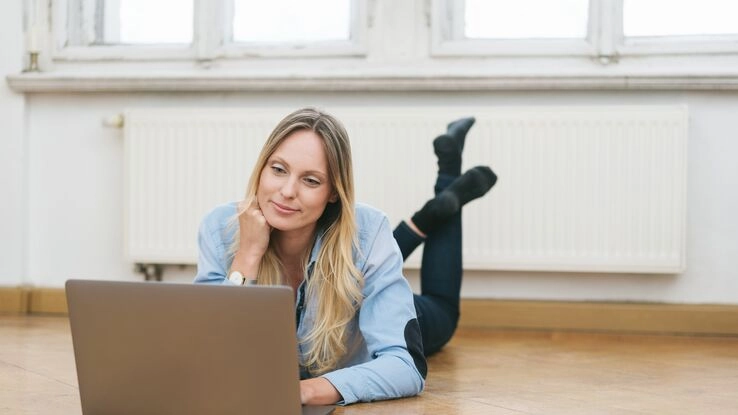 Eine Frau recherchiert am Laptop vor ihrer Heizung