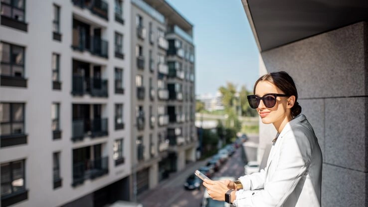 Immobilienmaklerin auf dem Balkon vor dem nächsten Kundentermin