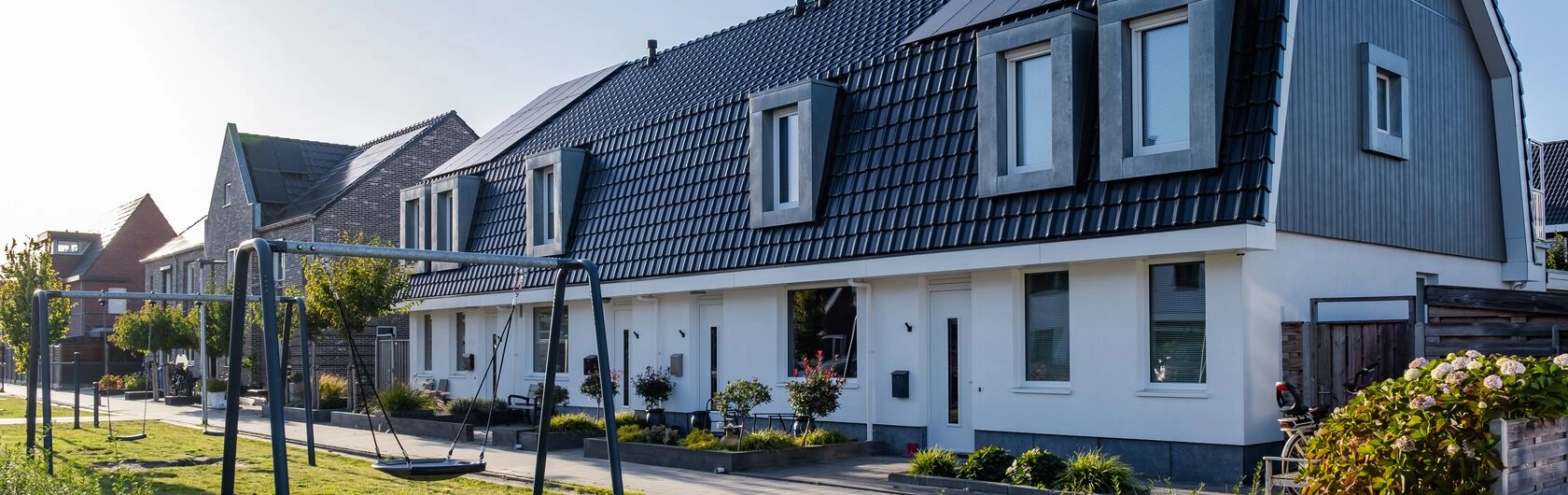 Das Foto zeigt ein Haus mit einem Spielplatz. Der Neubau symobilisiert regionale Fördermittel Bayern.