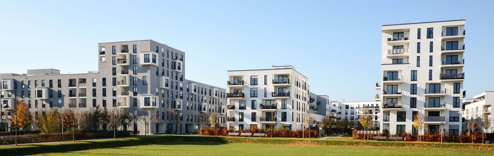 Regionale Fördermittel Brandenburg: Das Bild zeigt einige Neubauten mit vielen Wohnungen. Davor ist eine grüne Parkanlage zu sehen.