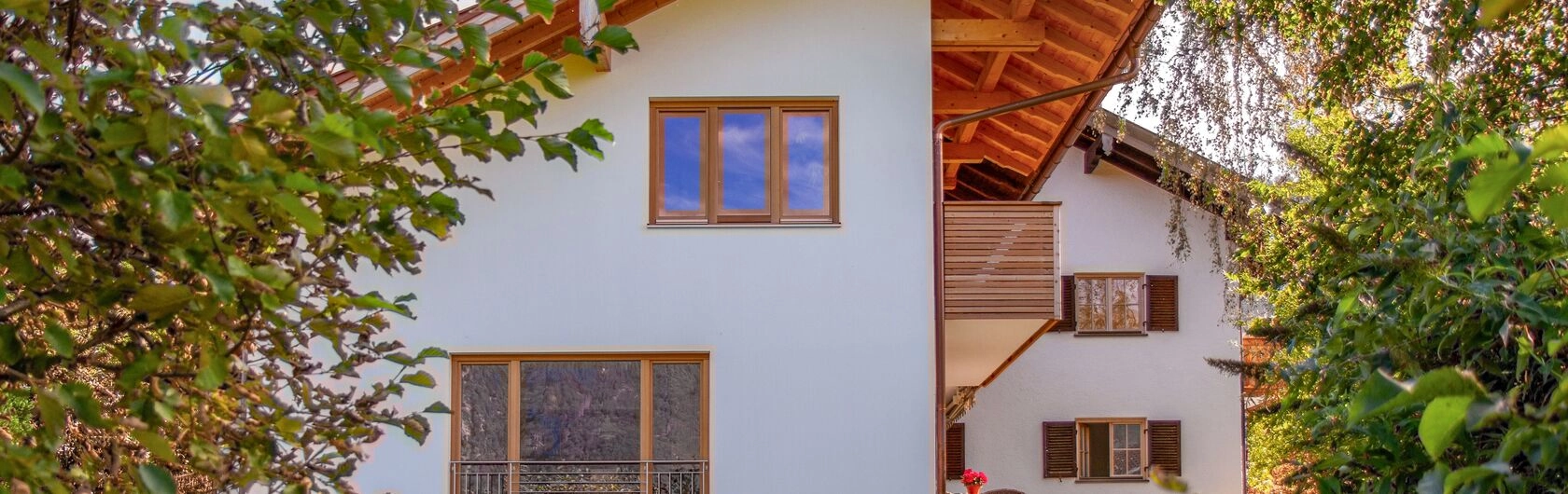 Symbolbild für Hauskauf mit Hilfe der Eltern: Ein Einfamilienhaus mit Holzrahmen bei Fenster und Türen.